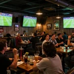 Catch the excitement of trực tiếp bóng đá hôm nay at a lively sports bar with fans cheering, drinks in hand.